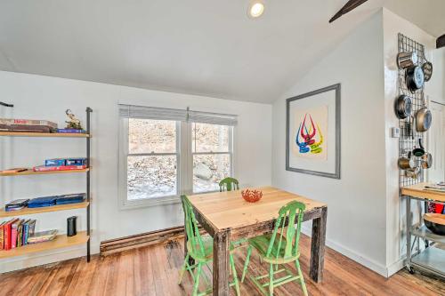 a dining room with a wooden table and green chairs at Chic Prattsville Studio with Private Hot Tub! in Prattsville
