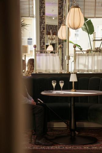 a person sitting at a table with two wine glasses at Continental du Sud in Ystad