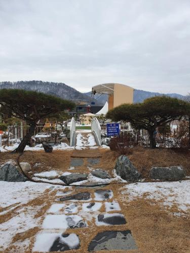 park ze śniegiem i drzewami oraz budynek w obiekcie MongGo MongGo Glamping w mieście Hongcheon