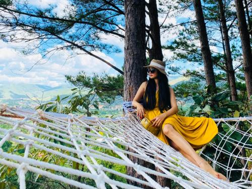 a woman in a yellow dress sitting on a hammock at Nacasoo hill in Tiên Hai