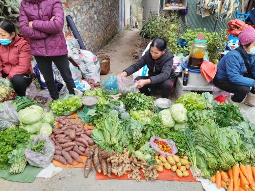 a group of people standing around a market with vegetables at Khách sạn Vườn Quốc gia Ba Bể in Bak Kan