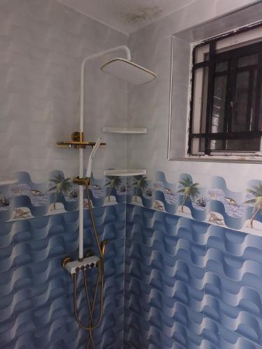 a shower with a blue and white shower curtain at Nungwi appartement- house in Nungwi