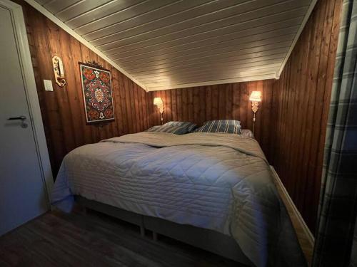 um quarto com uma cama grande e paredes de madeira em Koselig hytte med uteplas ved Hallingdalselva em Al