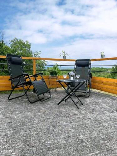 2 chaises longues et une table sur une terrasse dans l'établissement Trespouz'en, à Trespoux-Rassiels