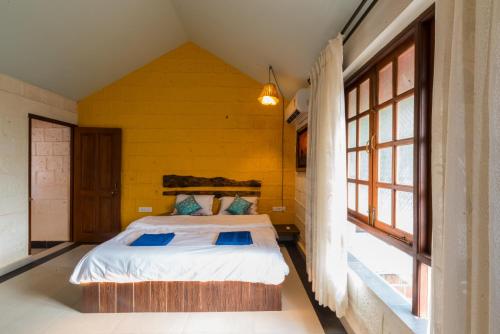 Avontade Suites في أنجونا: غرفة نوم بسرير في غرفة بجدران صفراء