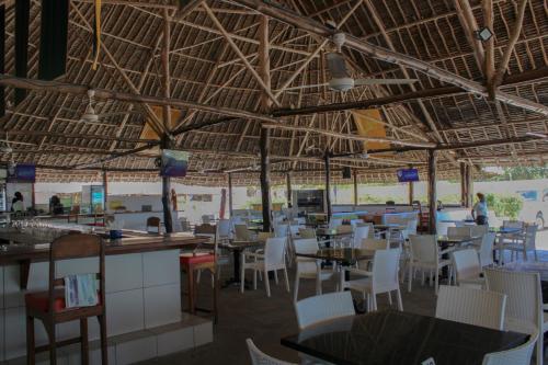 a restaurant with white chairs and tables and ceilings at The Beach House by Maasai in Mombasa