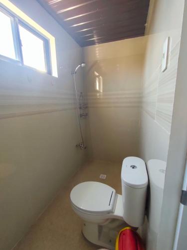 a bathroom with a white toilet and a window at JM's BnB Hauz Air-conditioned private room in Kalibo
