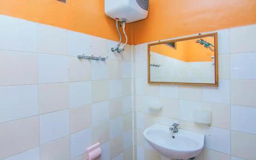 uma casa de banho com um lavatório branco e um espelho. em Kedin's Inn em Denpasar