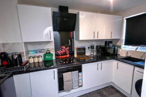 cocina con armarios blancos y encimera negra en I Love London! A STUNNING 2Bed Home Sleeps 1-4! en Thamesmead