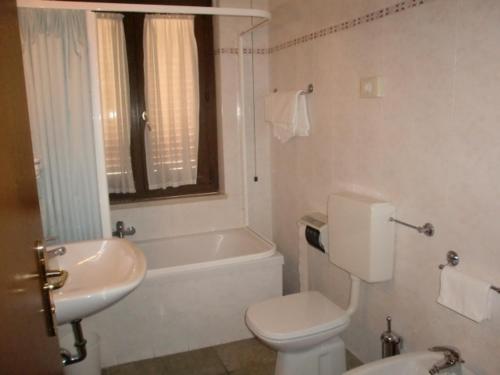 a white bathroom with a toilet and a sink at Hotel San Pietro in Assisi