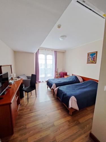 een slaapkamer met 2 bedden en een bureau met een computer bij Hotel Hunor in Sátoraljaújhely