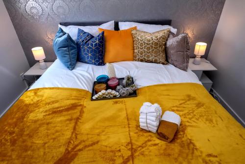 a bed with a yellow bedspread with a tray of food on it at I Love London! A STUNNING 2Bed Home Sleeps 1-4! in Thamesmead