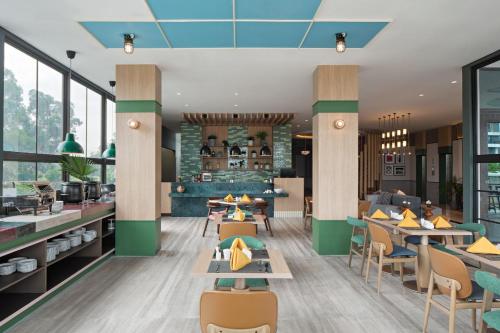 a rendering of a restaurant with tables and chairs at MaxOneHotels at Kota Harapan Indah-Bekasi in Bekasi