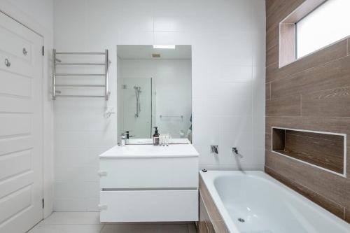 uma casa de banho branca com uma banheira e um lavatório e uma banheira em Elegant Federation Home Near The Airport em Sydney