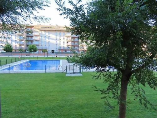 una piscina en un parque con un árbol en Precioso atico con bonitas vistas a la Peña Oroel en Jaca