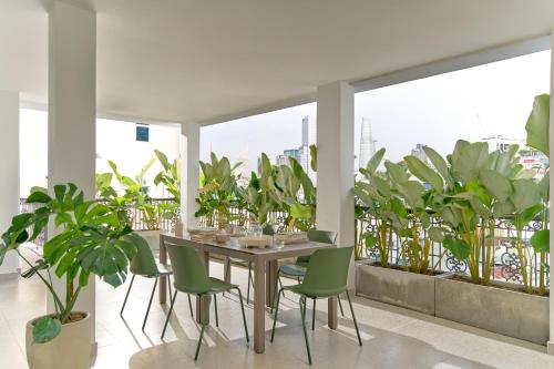 een eetkamer met groene stoelen en een tafel met planten bij M Village Nguyễn Du in Ho Chi Minh-stad