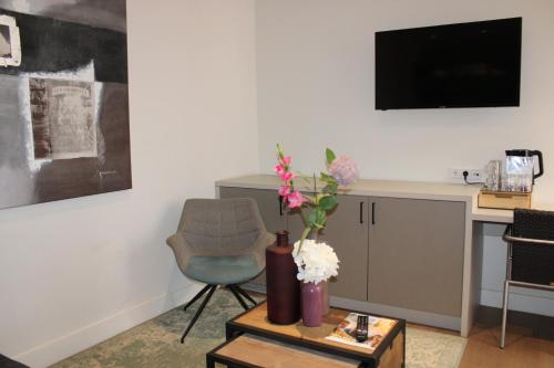 a living room with a chair and a table with flowers at Hotel 't Peperhuys in Kaatsheuvel