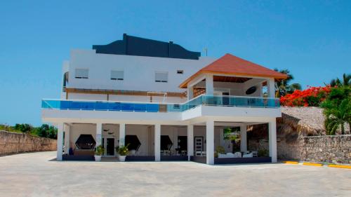 a large white building with a red roof at Hotel Capriccio Mare y Restaurante in Punta Cana