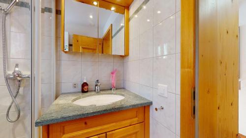 La salle de bains est pourvue d'un lavabo, d'un miroir et d'une douche. dans l'établissement Stambuoch, à Celerina