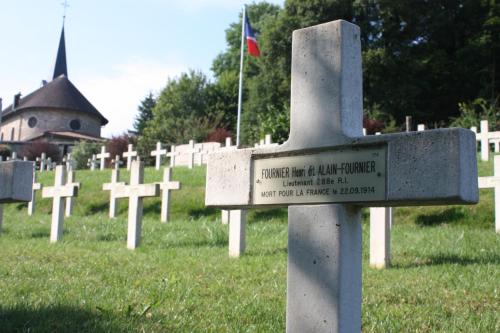 a cemetery with a cross in the grass with a flag at Gîte de la fontaine in Saint-Rémy-la-Calonne