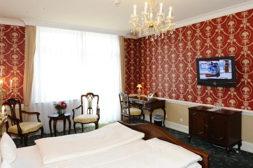 a bedroom with a bed and a desk and a tv at HELIOPARK Bad Hotel Zum Hirsch in Baden-Baden