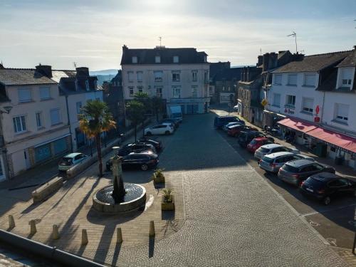 a city street with cars parked in a parking lot at Charmant studio proche canal. in Châteauneuf-du-Faou