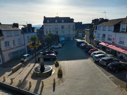 une rue de la ville avec des voitures garées dans un parking dans l'établissement Charmant studio proche canal., à Châteauneuf-du-Faou