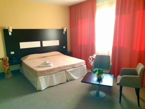 a bedroom with a bed and a chair and a table at Santa Loja Hotel Residence in Tito