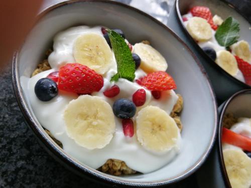 a bowl of yogurt with bananas and berries on it at Royal Highness Lux Guesthouse in Carletonville