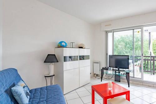 un salon avec un canapé bleu et une télévision dans l'établissement Le Lundi au Soleil - T3 à 250 m de la plage, à La Baule