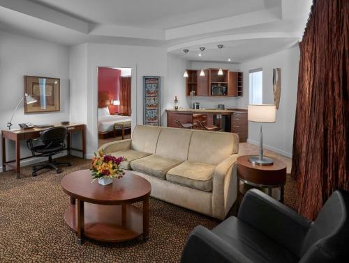 a living room with a couch and a desk and a kitchen at Metterra Hotel on Whyte in Edmonton