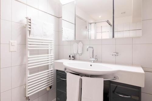 a white bathroom with a sink and a mirror at EMA House Serviced Apartments Seefeld in Zurich