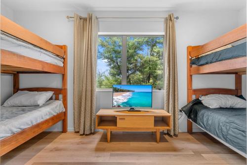 una camera con due letti e una scrivania con un computer di Manuka Sanctuary - Mangawhai Heads Holiday Home a Mangawhai