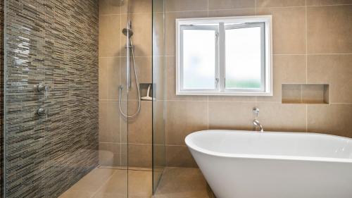 ein Badezimmer mit Badewanne und Fenster in der Unterkunft Remarkable Red Beach - Red Beach Holiday Home in Red Beach