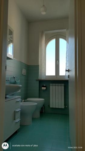 uma casa de banho com um lavatório, um WC e uma janela. em Appartamento Torri di Avvistamento em Porto Recanati