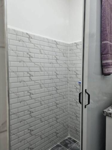a bathroom with a shower with a white brick wall at proche aéroport, idéal pour travailler in Marrakesh