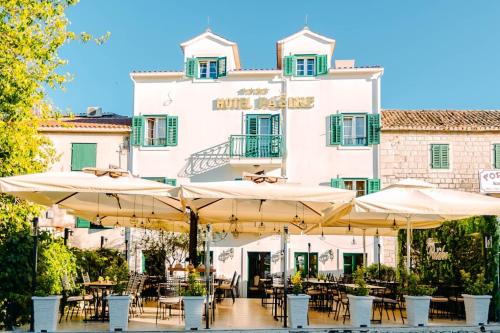 a restaurant with tables and umbrellas in front of a building at Heritage Hotel Pasike in Trogir