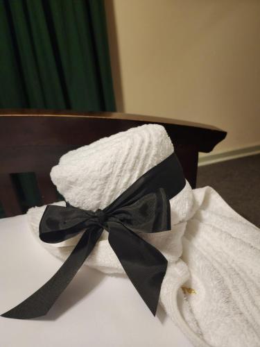a white towel with a black bow on a bed at Royal Highness Lux Guesthouse in Carletonville