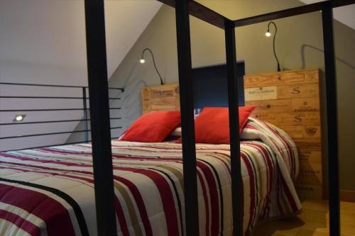 a bed with a black frame and red pillows on it at L'Aubergiste in Corcelles-les-Arts
