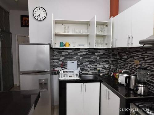 a kitchen with white cabinets and a clock on the wall at Departamento entero con vista al río in Iquitos