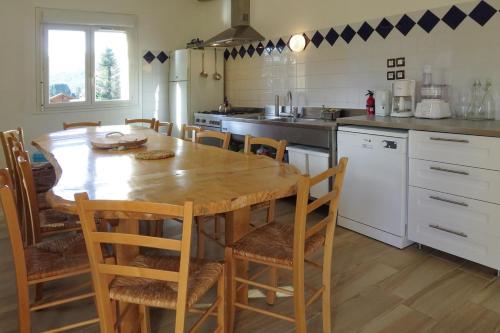 une cuisine avec une table en bois et quelques chaises dans l'établissement Gîte SOLDANELLE - 15 personnes - 