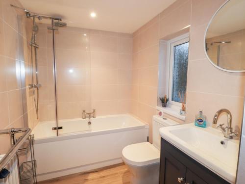 a bathroom with a tub and a toilet and a sink at Little Barn Cottage in Newport Pembrokeshire
