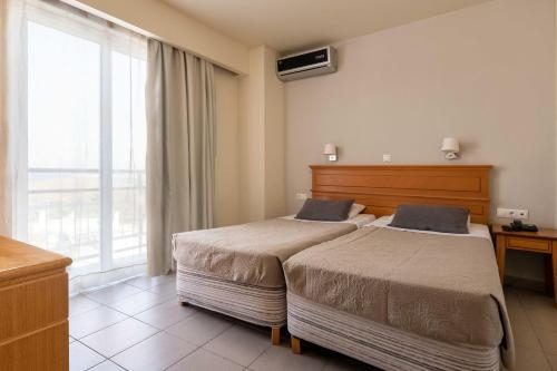 pokój hotelowy z 2 łóżkami i oknem w obiekcie City Plus Rhodes Hotel w mieście Rodos