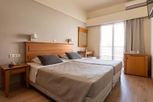 sypialnia z dużym łóżkiem i dużym oknem w obiekcie City Plus Rhodes Hotel w mieście Rodos