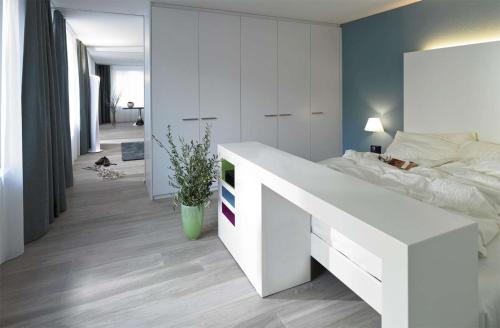 a bedroom with a white bed and a white desk at City Apartments in Zug