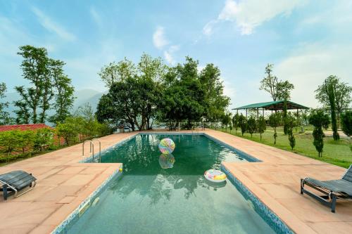 a swimming pool in a yard with two chairs at Neer Ganga Resorts in Rishīkesh