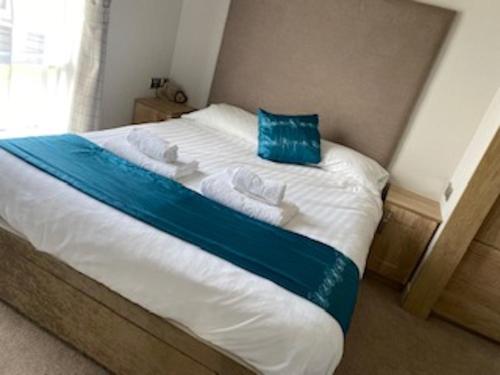 a bed with a blue pillow on top of it at Morwenna Lodge in Bude