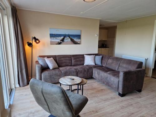 a living room with a brown couch and a table at Vakantiewoning Meidoorn in Meliskerke