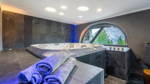 a large bathroom with a tub and a large window at Chalet Monti Della Luna 7, Emma Villas in Bousson