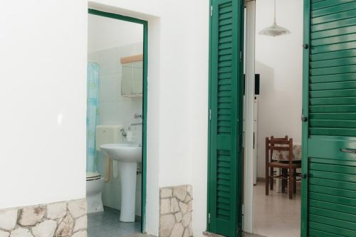 a bathroom with a green door and a sink at Pescoluse Houses in Marina di Pescoluse